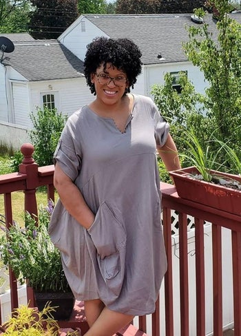 Reviewer wearing an oversized taupe color knee-length dress with large pockets
