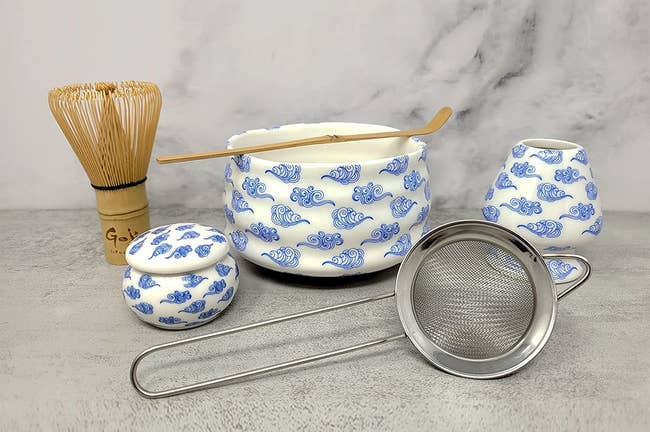 white and blue ceramic matcha set with a whisk and strainer