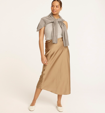 a model wearing the slip skirt in camel with a grey tank top