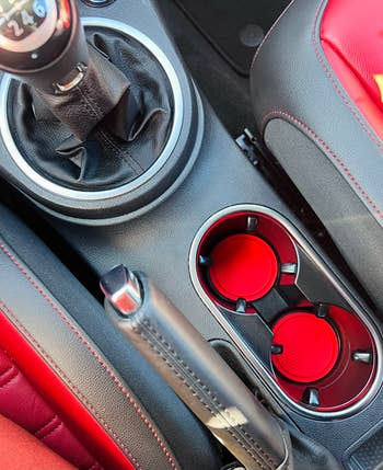 reviewer photo of their car's console with red coasters in two cup holders