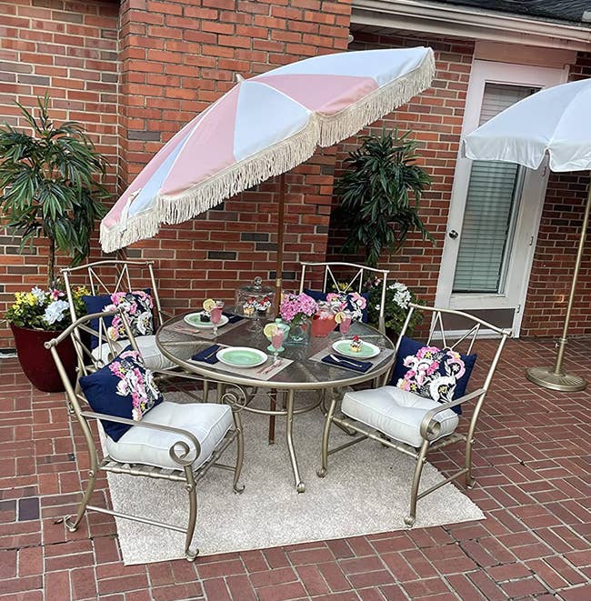 reviewer's pink and white striped umbrella with fringe on an outdoor table 