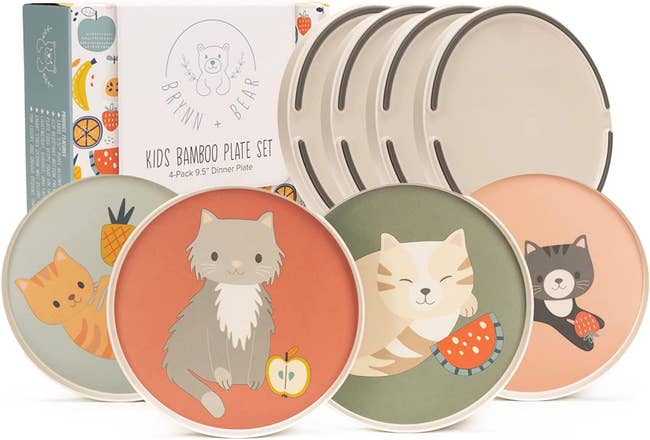 Four plates with cats playing with fruit placed in front of product packaging; back of plates with silicone bottom also shown.