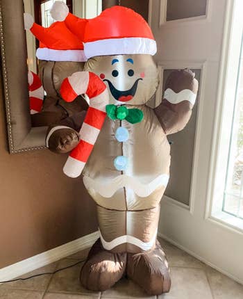 reviewer photo of the inflatable gingerbread person inside their house near their front door
