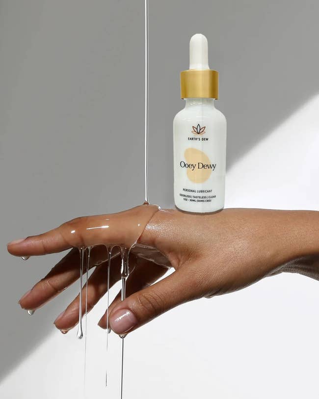 model with lubricant dripping all over hand and bottle resting on hand