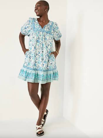 Model in blue and white patterned short sleeve flowing dress with tassels on collar 