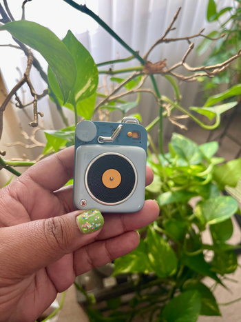 a buzzfeed staff writer holding the mini speaker in blue