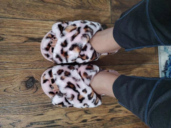 Person wearing plush, animal print slippers indoors, suitable for a cozy at-home shopping recommendation