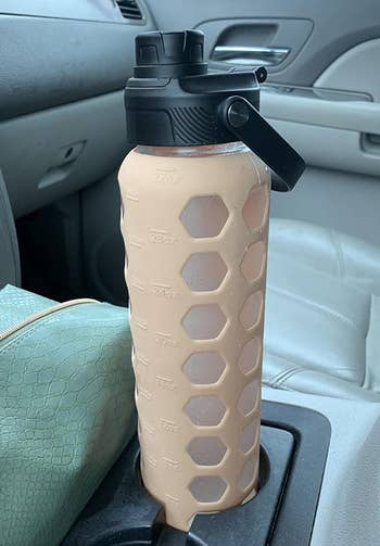 a reviewer's brown water bottle in a car cupholder 
