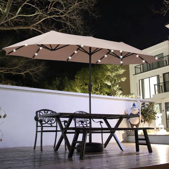Patio umbrella with built-in lights implicit an outdoor eating acceptable connected a deck. Garden gnome decoration disposable successful the background