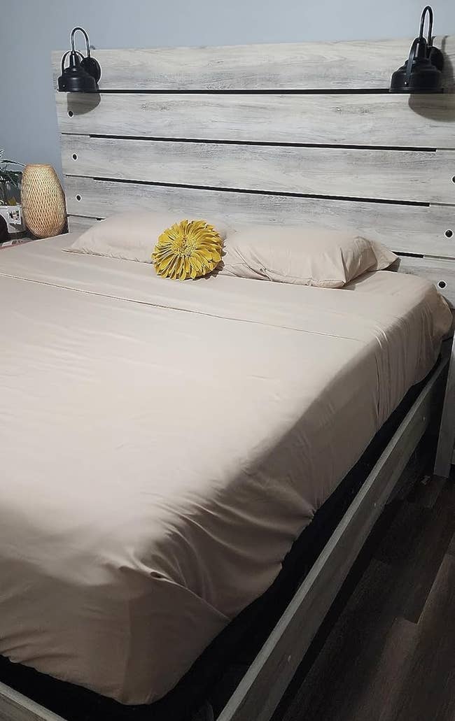 A reviewer's neatly made bed with a decorative yellow pillow, set in a cozy room with wall art