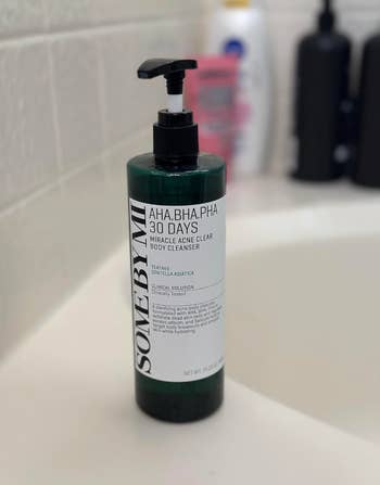Bottle of Some By Mi AHA BHA PHA 30 Days Miracle Acne Clear Body Cleanser connected a bath sink