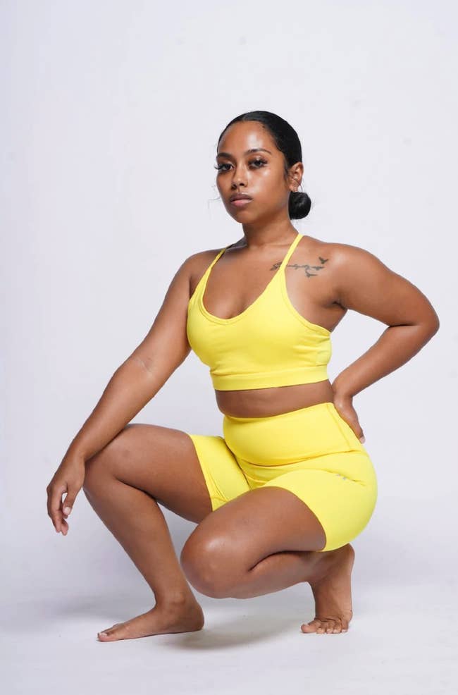 model in yellow strappy sports bra and matching bike shorts
