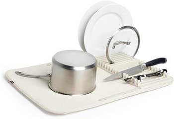 Compact dish rack with pots, a plate, and cutlery drying on a mat