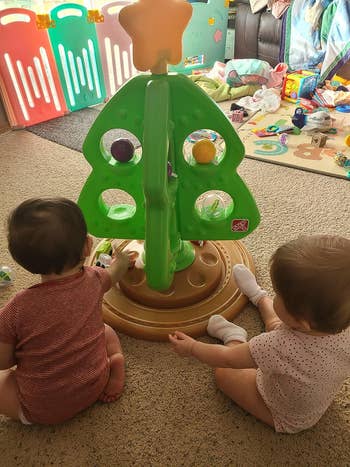 babies playing with a plastic toy christmas tree
