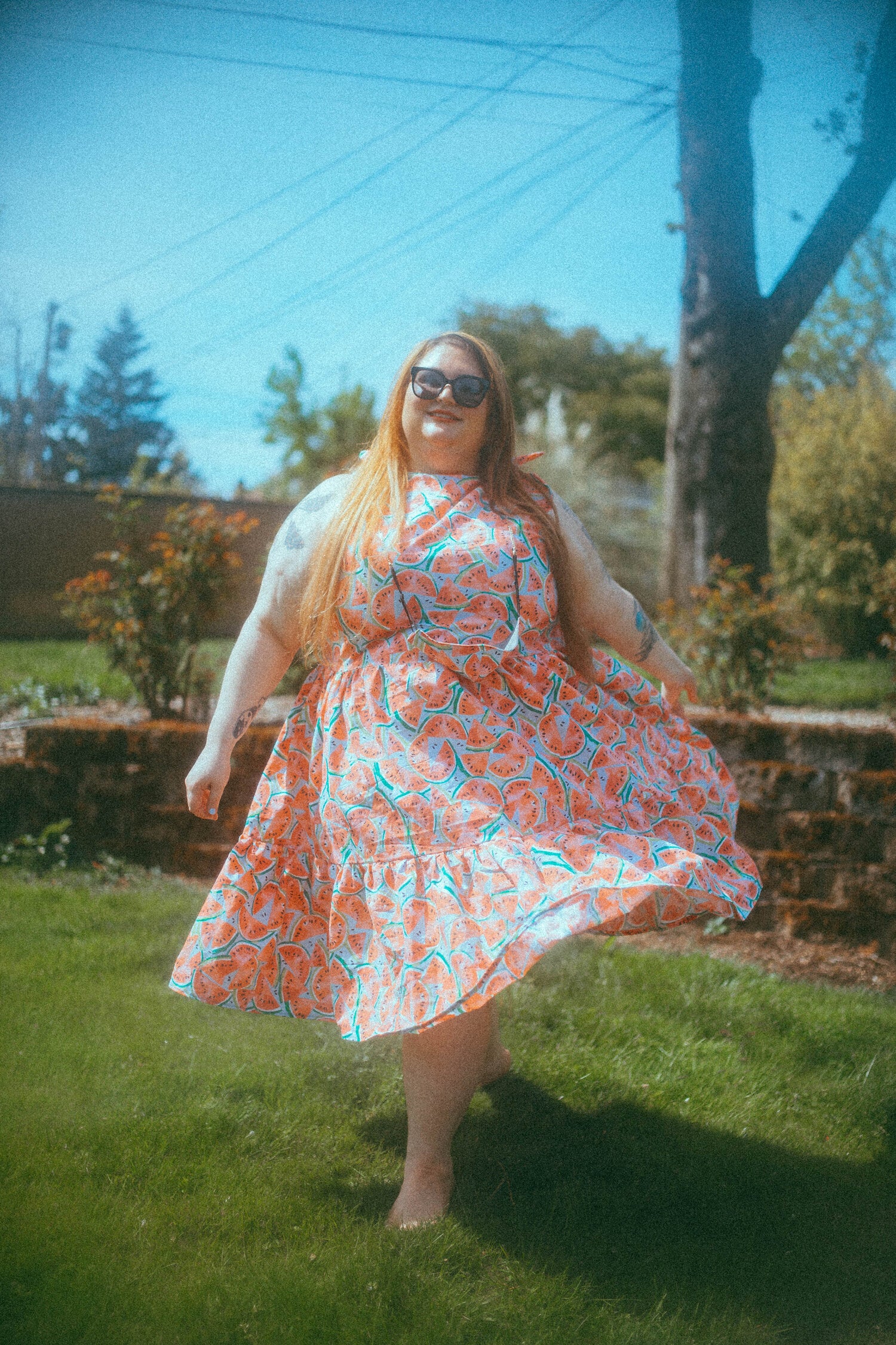 Plus-size model waring a light blue midi dress with watermelons on it