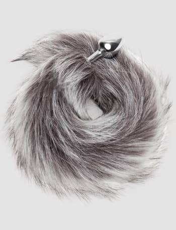 Faux fur process    accessory with a small, shiny metallic plug attached, styled successful  a circular shape. Featured successful  a buying  context