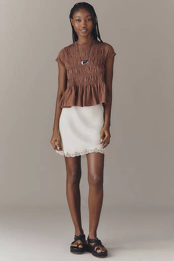 Person wearing a crinkled blouse, lace-trimmed skirt, and sandals, lasting  confidently successful  a workplace  setting. Ideal for summertime  buying  features