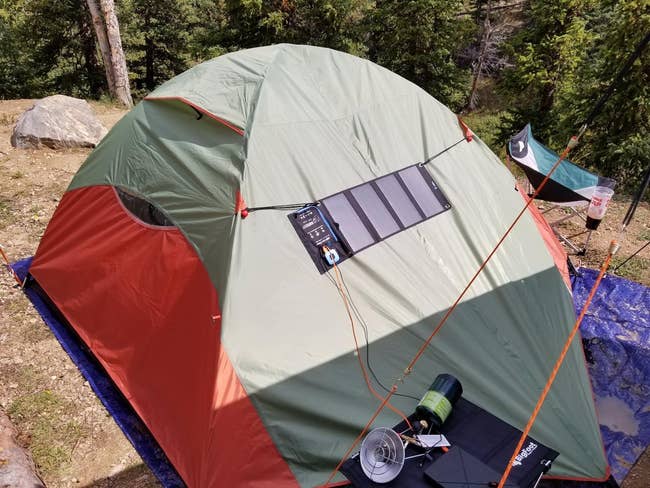 Solar panel attached to a camping tent in a wooded area for charging devices outdoors