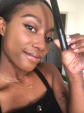 BuzzFeed editor holds up eyeliner tube while wearing it with a cateye