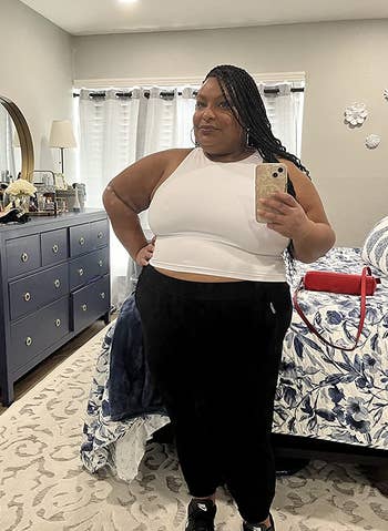 a reviewer wearing the sleeveless crop top in white with black workout leggings 