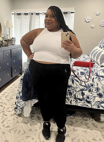a reviewer wearing the sleeveless crop top in white with black workout leggings 