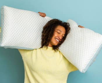 model smiling and holding up 2 pillows successful antithetic sizes