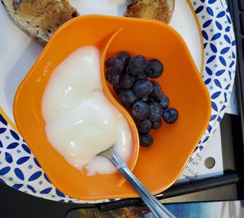 a small hexagon shaped orange bowl split into two sides, one with yogurt and one with blueberries 