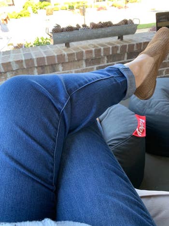 Person successful  casual bluish  jeans and woven shoes relaxing connected  a patio. A container  of Lay's chips is adjacent    connected  a beanbag chair