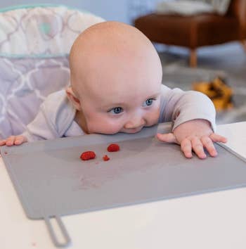 baby biting the edge of the placemat places in front of them