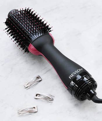a reviewer showing an up close photo of the hot air brush with silver hair clips