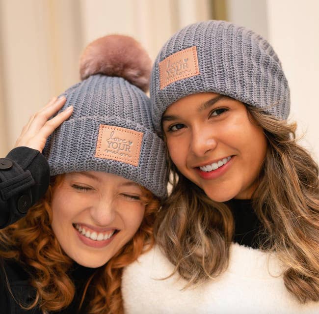 two models in charcoal beanies with glittery love your melon labels on them