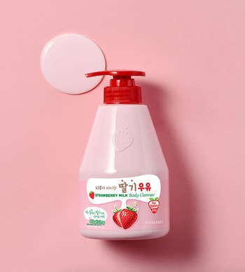 Bottle of strawberry beverage  assemblage  cleanser with pump, featuring strawberry illustrations connected  label, placed against a plain backdrop