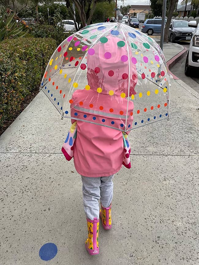 reviewer image of a kid walking holding the umbrella over their head