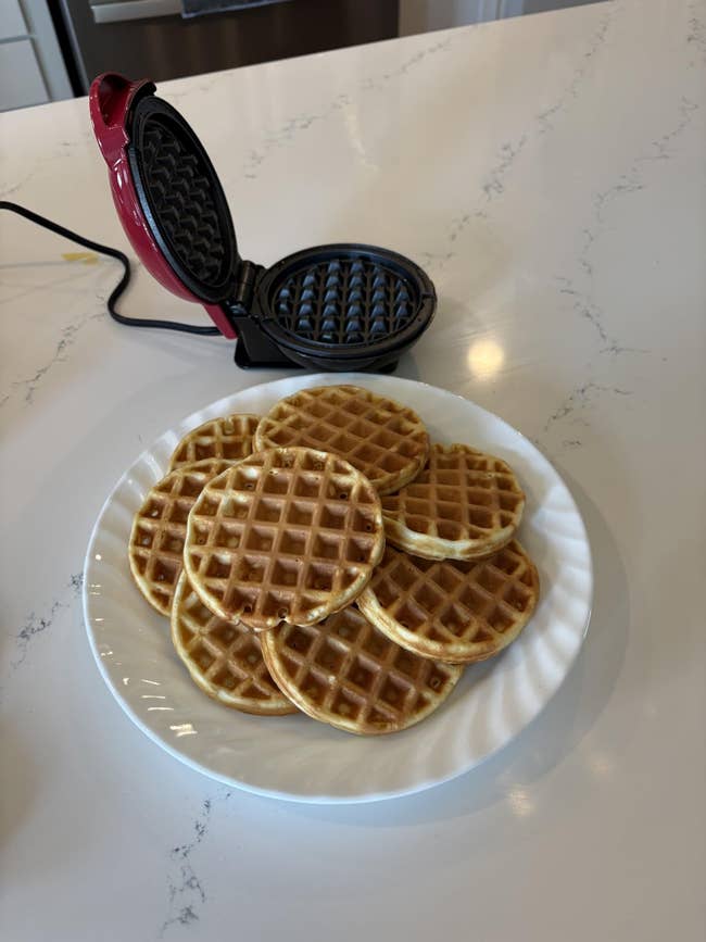 A sheet  of mini waffles adjacent  to an unfastened  waffle shaper  connected  a room  counter