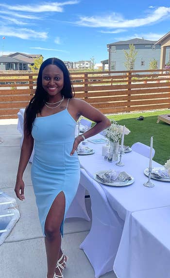reviewers in chic one-shoulder dress standing at outdoor dining setup