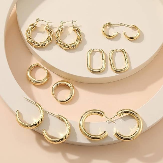 Assorted styles of gold hoop earrings displayed on a flat surface