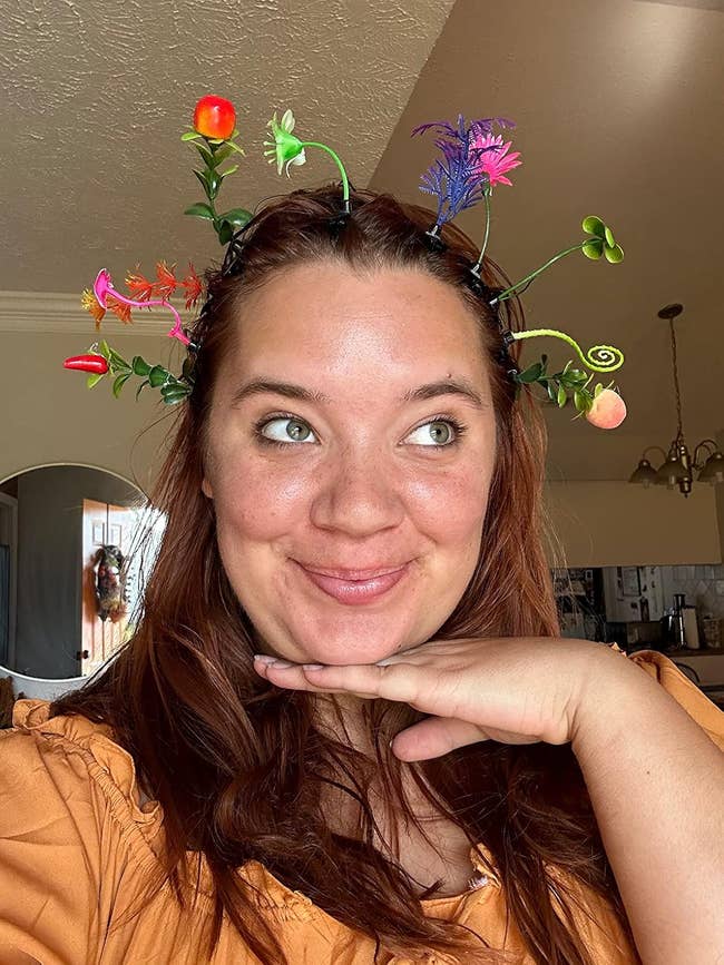 Person wearing whimsical headband with colorful floral and effect   decorations
