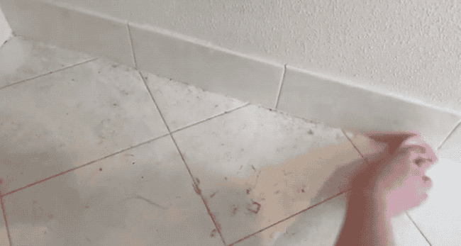 A gif of a reviewer removing dust rom a tile floor and showing it collect on the ridges of the damp duster