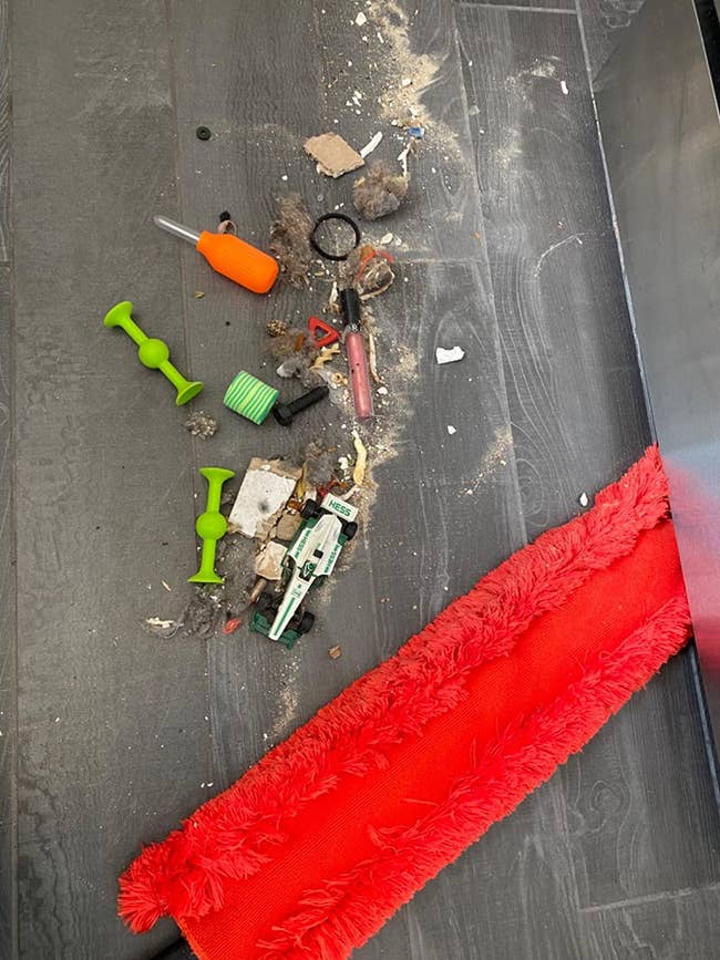 reviewer image of a mound of dirt and random small objects the duster removed from under a fridge