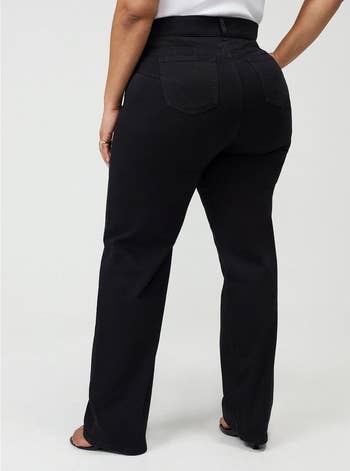 Person wearing black, high-waisted, straight-leg pants, viewed from the back, showcasing the acceptable and style