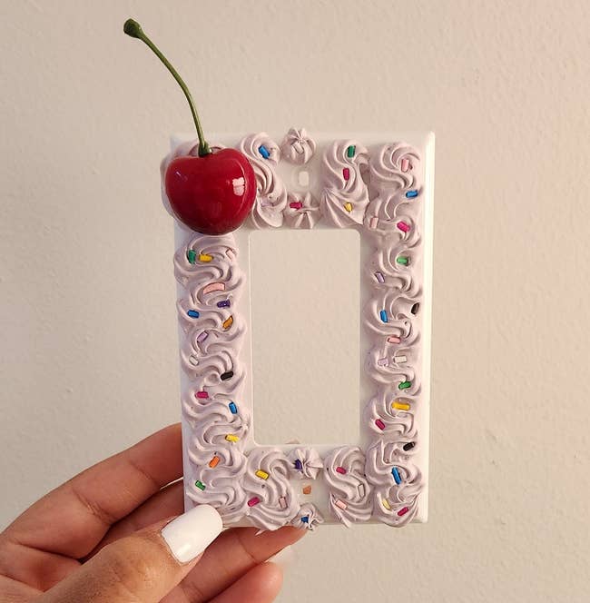 Hand holding a decorative frame with a cherry on top, suitable for shopping home decor