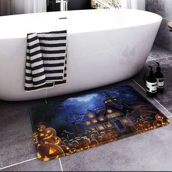 the pumpkins and haunted house bathmat by a tub