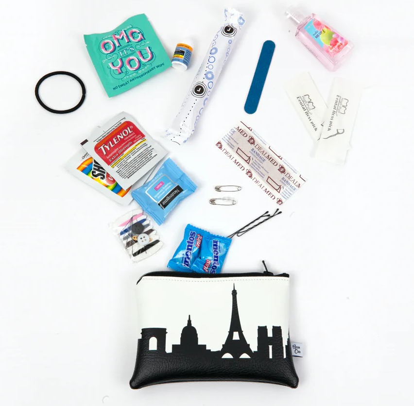 A black-and-white storage pouch with the Paris skyline on it next to a variety of mini emergency items that come in the kit