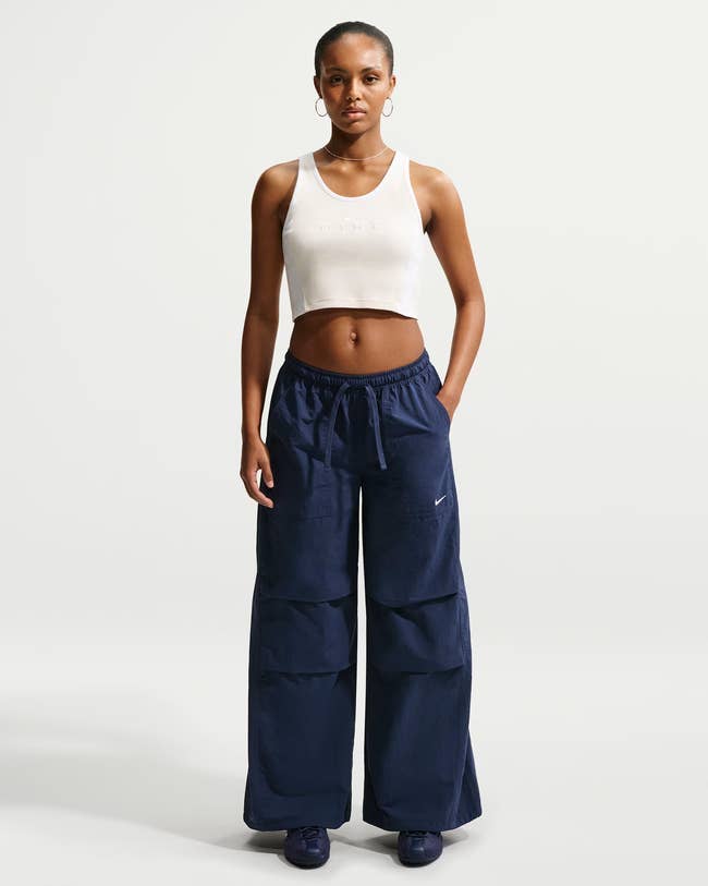 Person wearing a fitted vessel  apical  and wide-leg pants with pockets, lasting  against a plain background