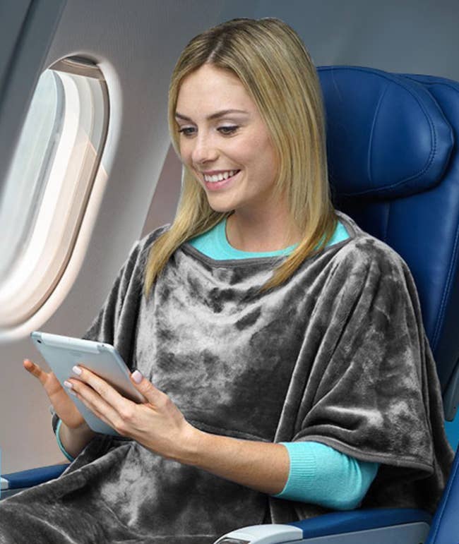 Model wearing the grey poncho on a plane