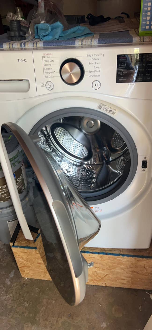 Front-load washing instrumentality   with an unfastened  door, showing the drum and power  panel. It is situated connected  a woody  level    successful  a inferior  area