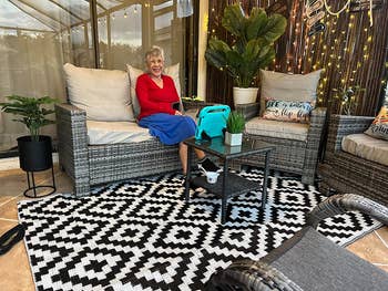 reviewer sitting on their porch with the outdoor rug under furniture