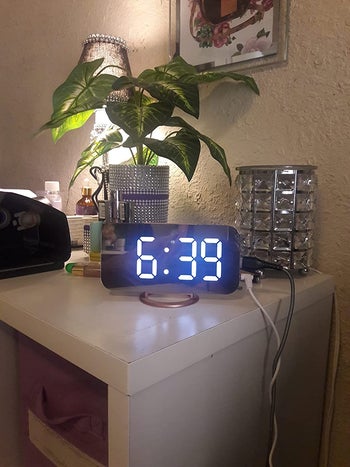 mirrored digital alarm clock on nightstand with plant