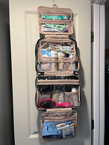 the toiletry bag hanging on a door with all the toiletries loaded inside