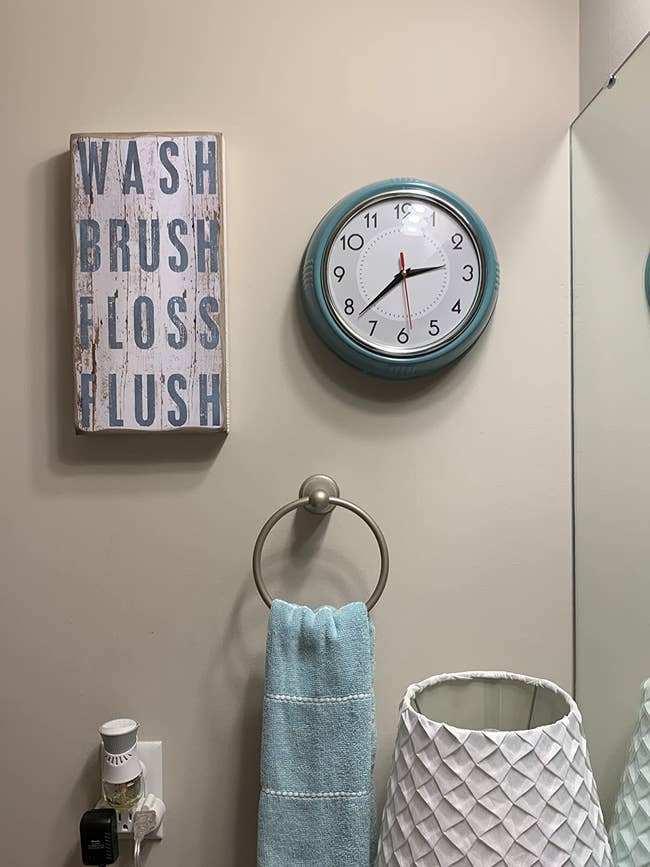 The round analog retro clock in pastel blue on a bathroom wall 